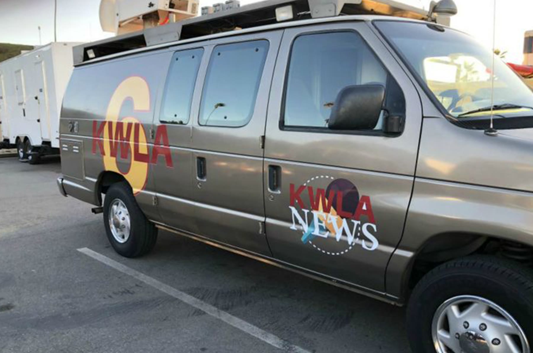 Silver news van with a station logo